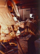 Photo of artist Bill Reid carving a large wooden sculpture