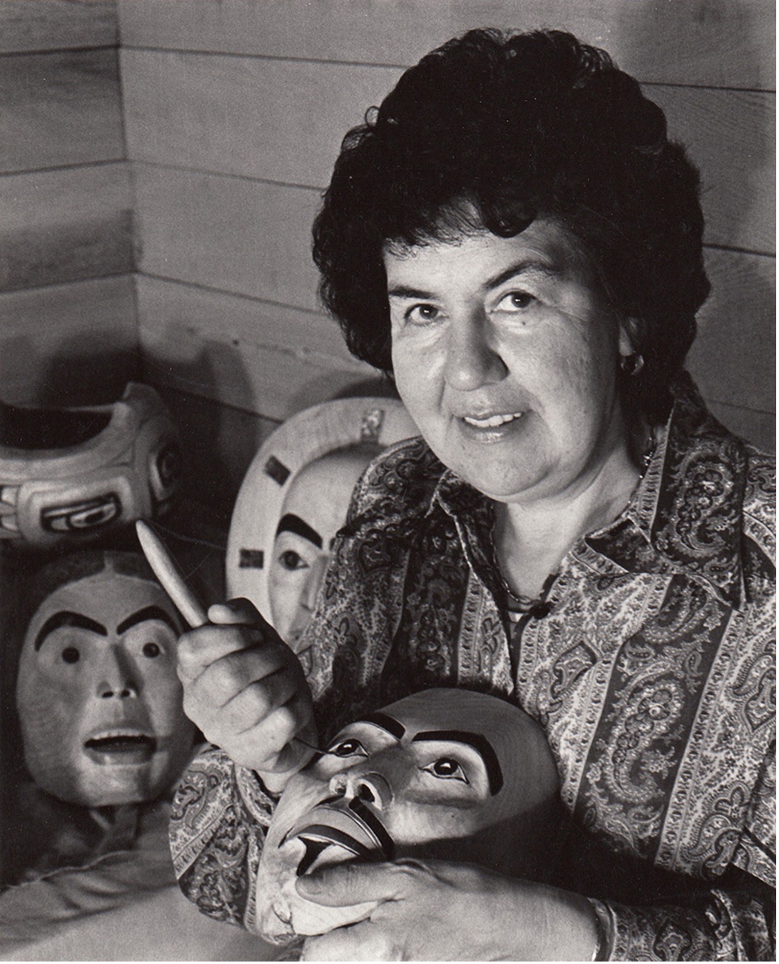 black and white photo of Freda Diesing with carving tool in hand carving a mask