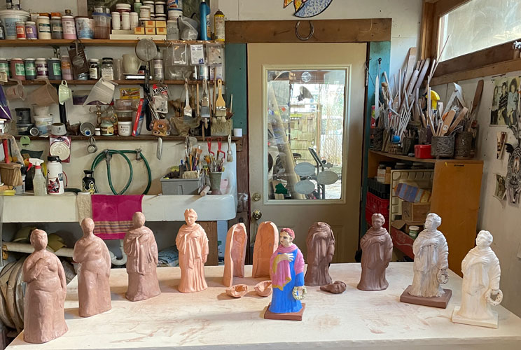 Photo of contemporary Tanagra figurines shown on a table in a studio in various stages of completion created by Ana Vizurraga