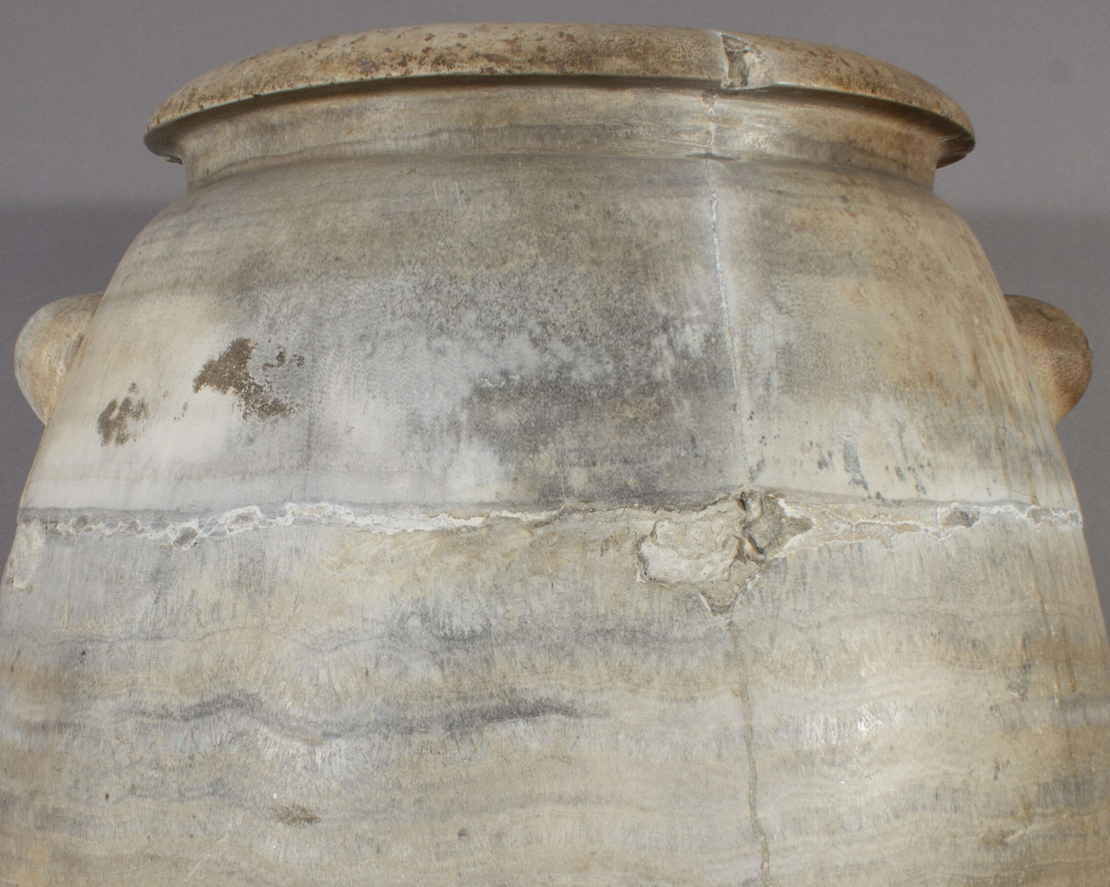 Detail of cracked discolored repairs to stone storage jar.