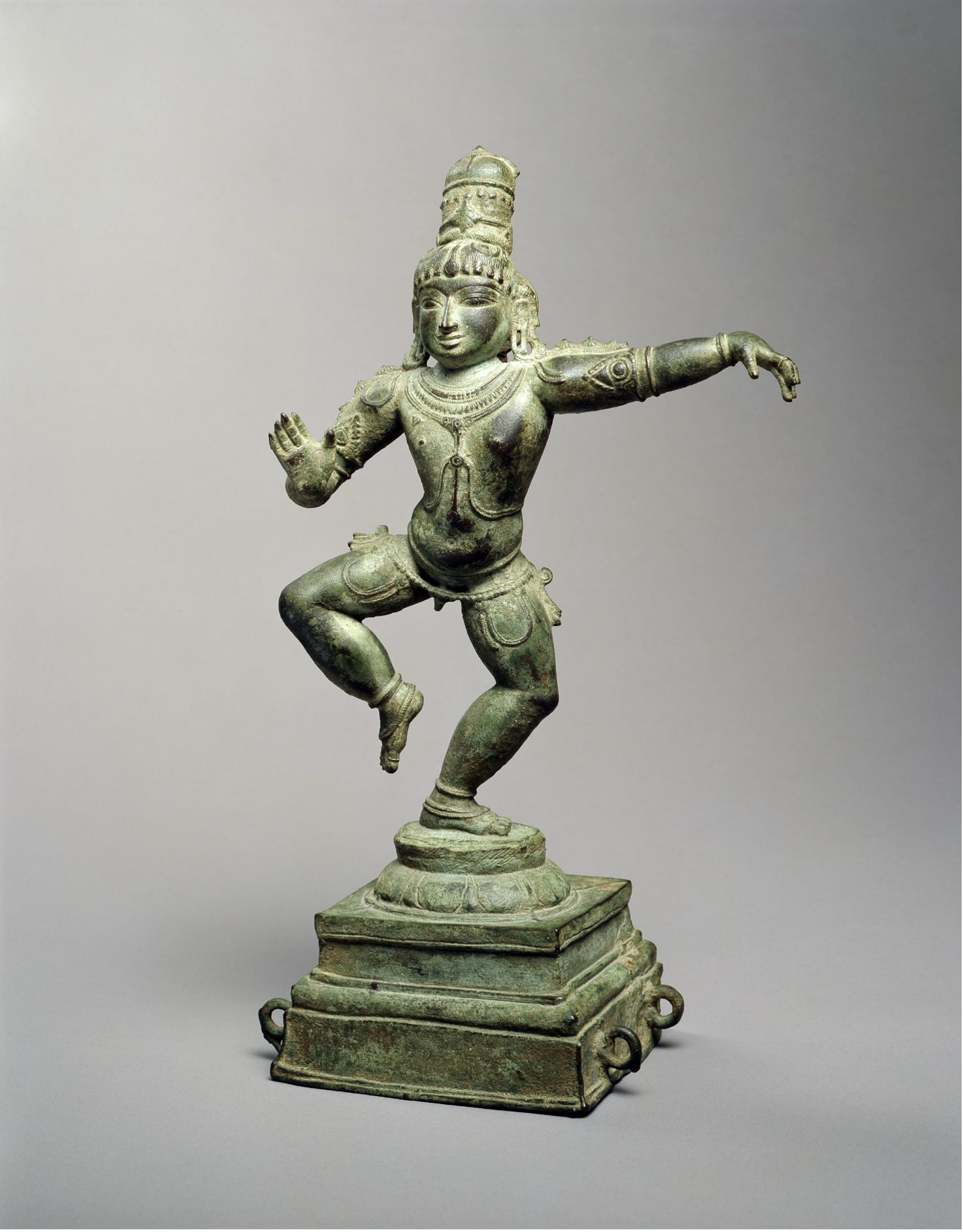 Dancing Balakrishna statue with dynamic pose, left arm extended, standing on one leg on top of pedestal 