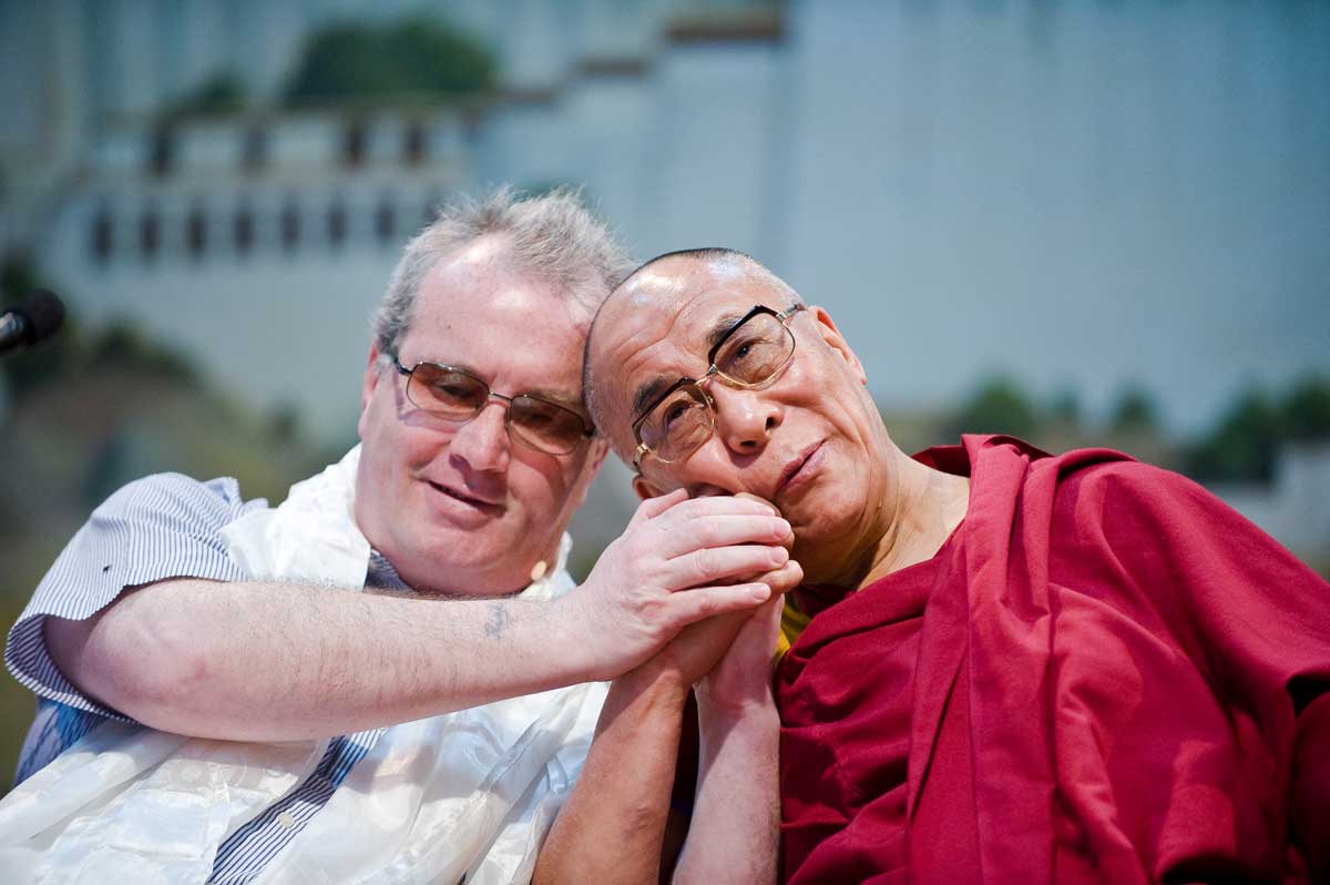 Richard Moore on the left and His Holiness the 14th Dali Lama on the right holding hands and heads touching
