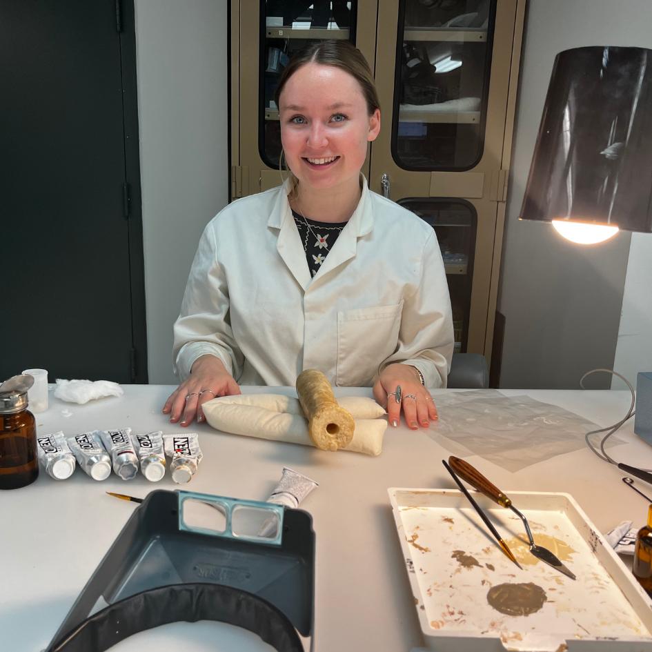 Ella Andrews, Mellon Fellow in Conversation sitting at table with artifacts and tools