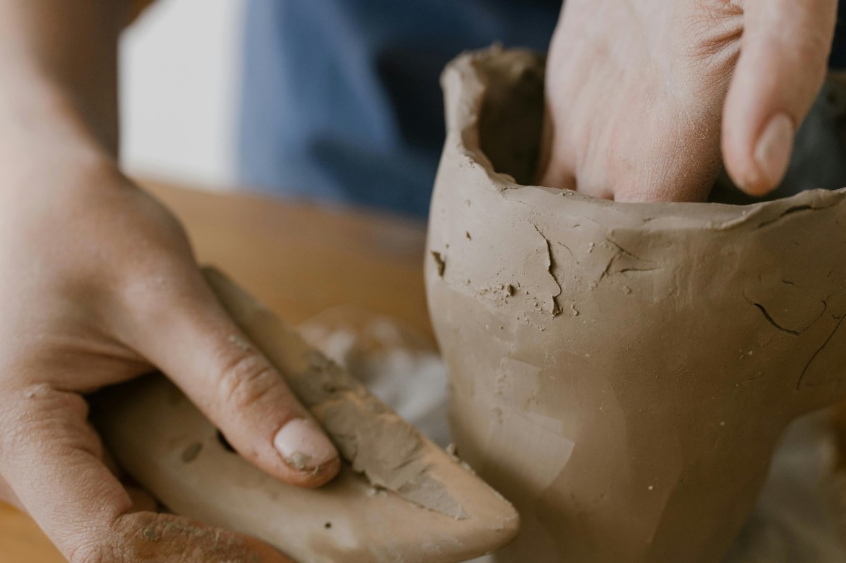 Hands with tool sculptuing clay