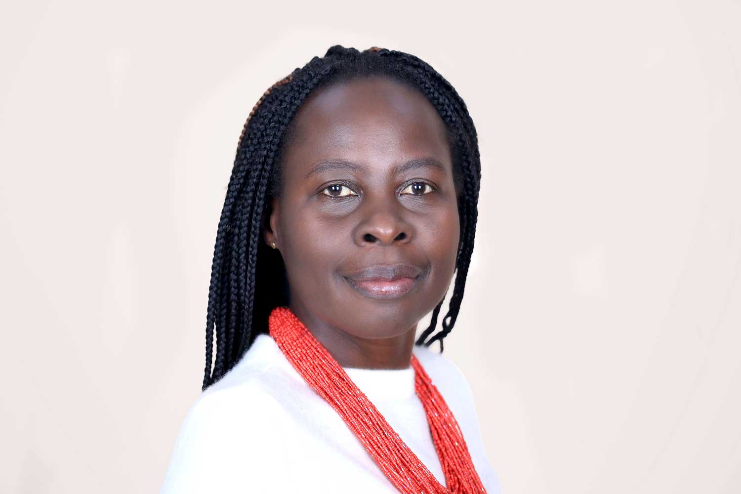 Photo of Margaret Nagawa on a tan background, wearing a white shirt a beaded red necklace