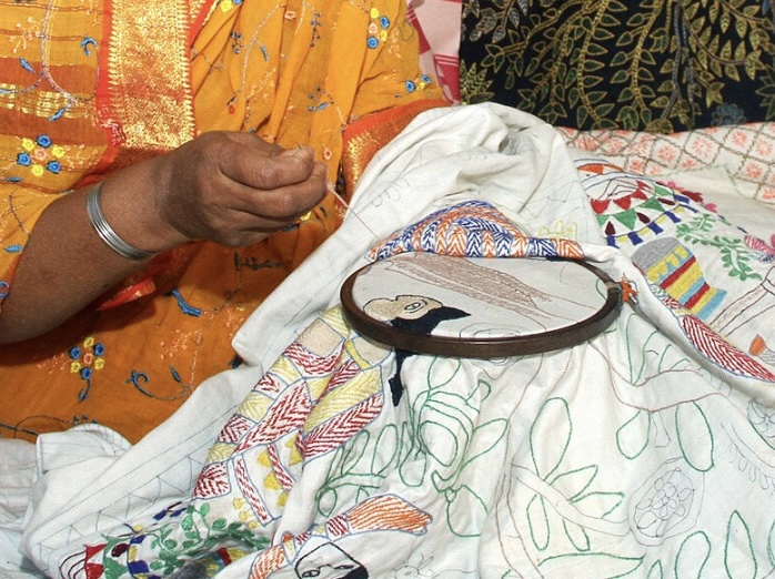 Colorful photo of someone embroidered quilts in Nakshi Kantha tradition
