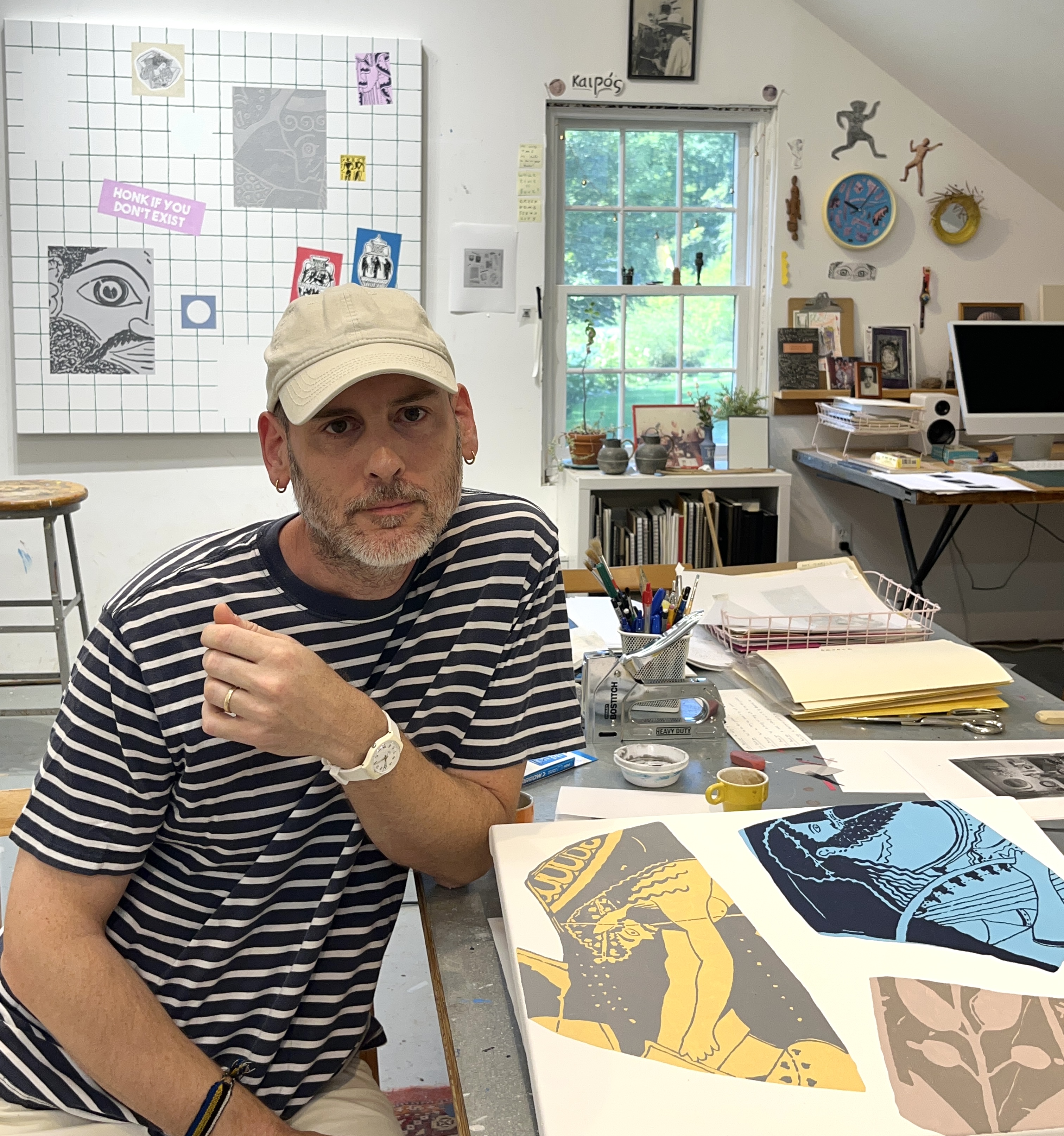 Artist Timothy Hull is on the right, sitting at a table in his studio with a new painting on the table