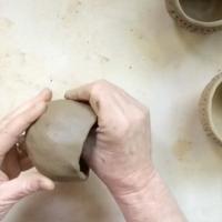Hands making a pinch pot out of clay