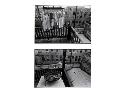 Two horizontal black and white photographs by Tom Dorsey. The photo on the top is taken while standing outside on a third-floor wooden deck. A clothesline hangs from left to right with eight long white t-shirts hanging from it with wooden clothes pins. A large brick building with dark windows stands in the background. The photo on the bottom is taken from the second-floor porch from a similar vantage point as the above image. There is a table with a circular grill on top in the foreground. 
