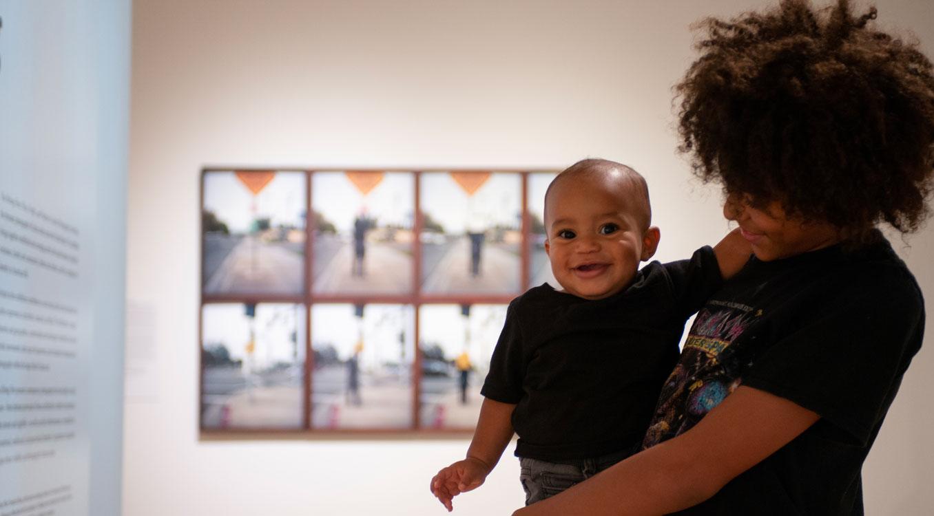 Person holding a small child smiling in the gallery