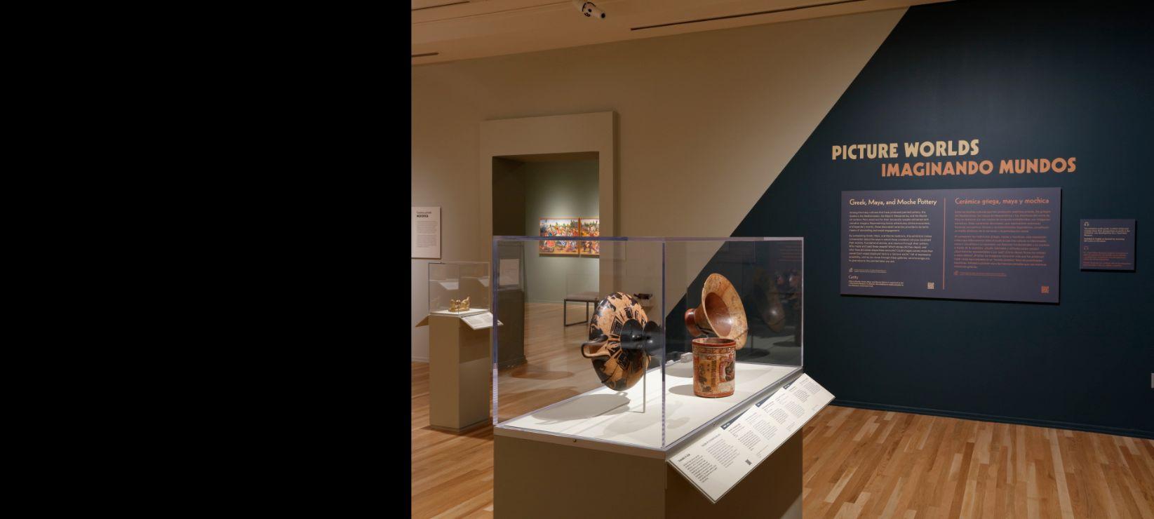 Installation image of Picture Worlds exhibition with case of ceramic objects in foreground and title wall in the back