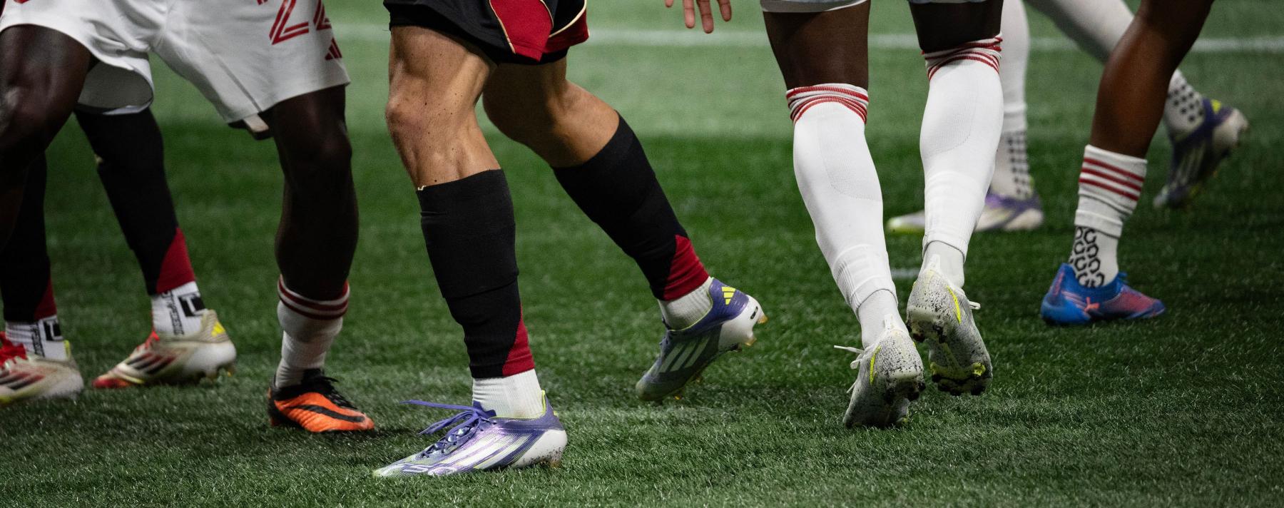 cropped photography by Sheila Pree Bright showing soccer players' legs and feet moving on the field during a soccer game 