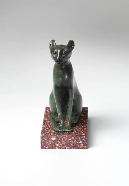 Bronze Egyptian Statuette of a seated Cat facing forward, green in color with a red stone base