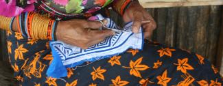 Woman uses scissors to create a mola